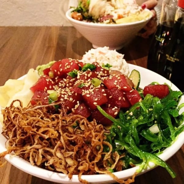 Close-up of a Toro Sushi Poke House poke bowl with tuna, seaweed, crispy onions, and ginger.