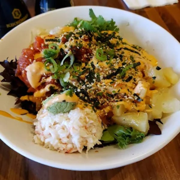 A vibrant Toro Sushi Poke House poke bowl with tuna, crab, pineapple, and sauces.